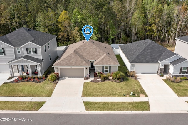 view of front of home featuring a garage, driveway, a forest view, and a front yard