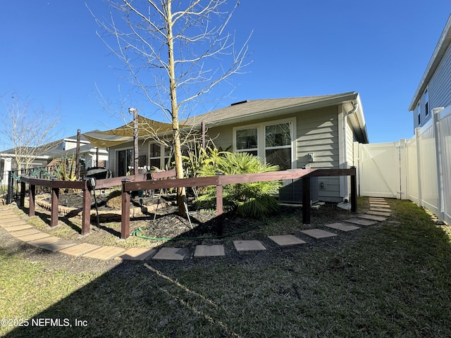 rear view of property featuring a yard, fence, and a gate