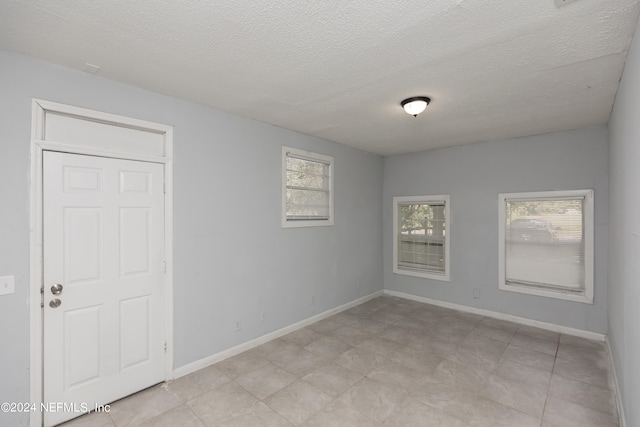 spare room with light tile floors and a textured ceiling