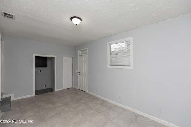 unfurnished room featuring light tile floors and a textured ceiling