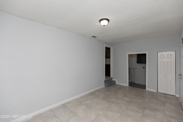 unfurnished bedroom with a textured ceiling and light tile flooring