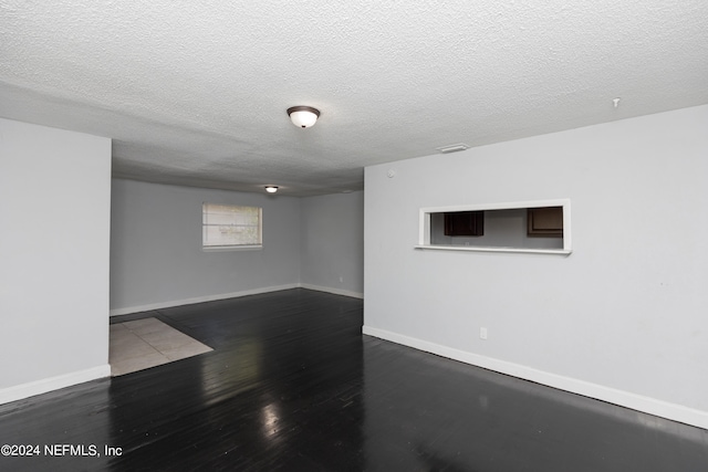 empty room with a textured ceiling and dark hardwood / wood-style floors