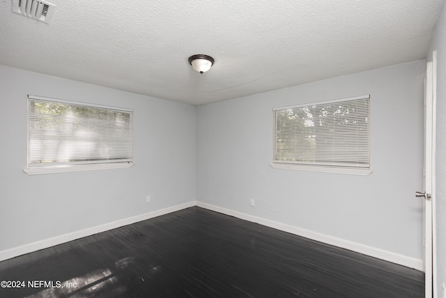 spare room featuring a textured ceiling and dark hardwood / wood-style floors