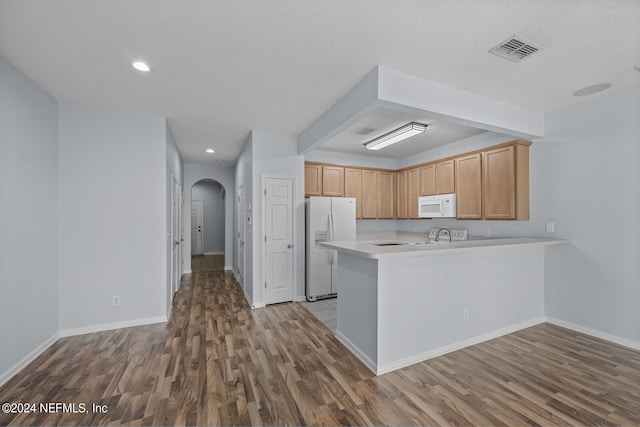 kitchen with dark hardwood / wood-style floors, white appliances, and kitchen peninsula