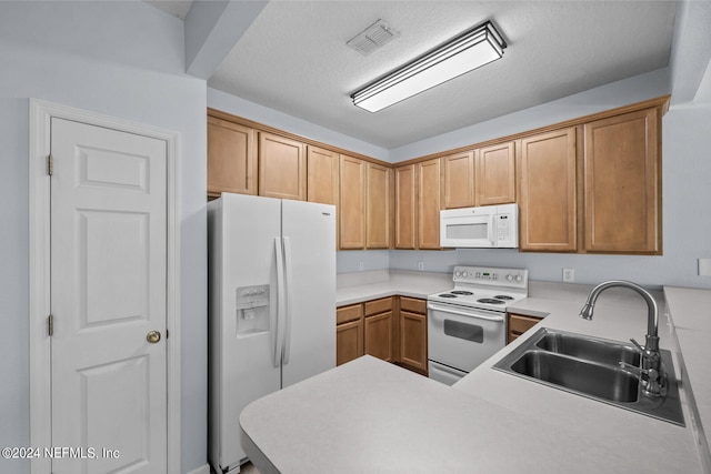 kitchen with a textured ceiling, sink, white appliances, and kitchen peninsula