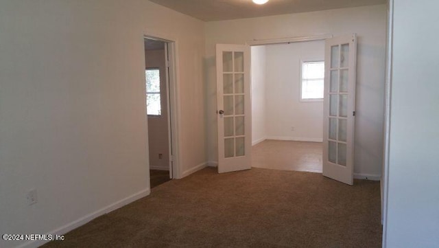 spare room with french doors and dark carpet