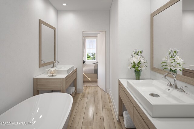 bathroom featuring a bathing tub, hardwood / wood-style floors, and dual vanity