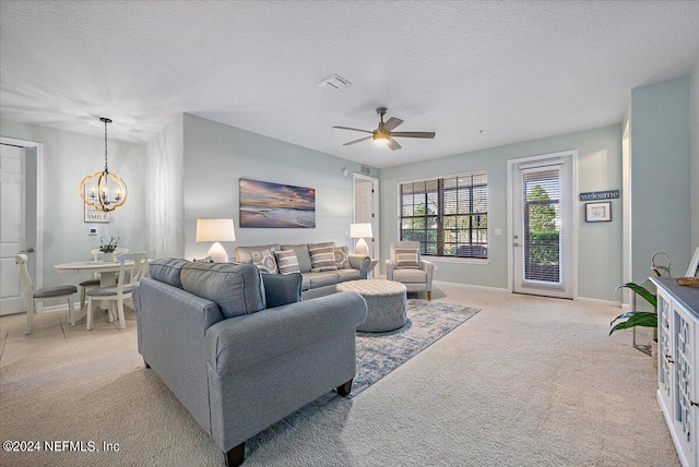 carpeted living room with a textured ceiling and ceiling fan with notable chandelier