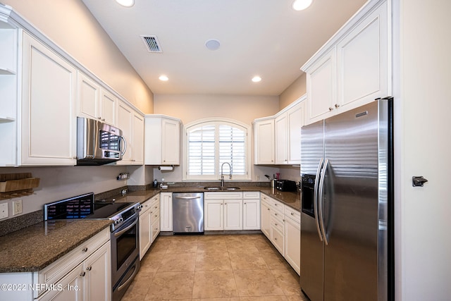 kitchen featuring light tile patterned flooring, sink, white cabinetry, appliances with stainless steel finishes, and dark stone countertops