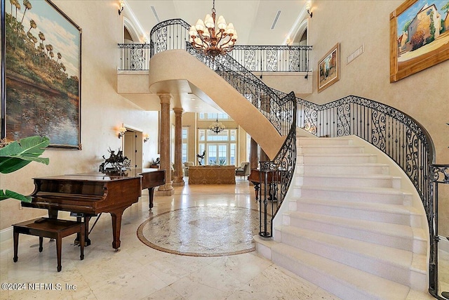 foyer with an inviting chandelier, a towering ceiling, and ornate columns