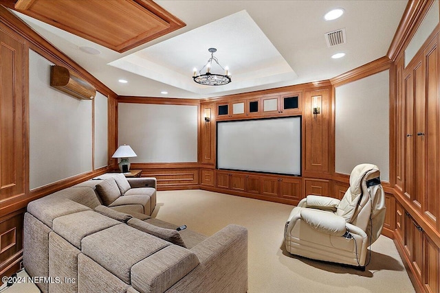 home theater room with a raised ceiling, carpet flooring, ornamental molding, a wall mounted air conditioner, and a notable chandelier