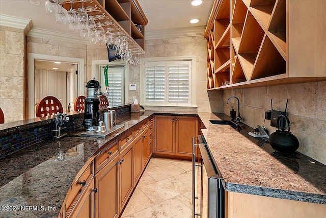 kitchen featuring tile walls, dark stone counters, ornamental molding, and sink