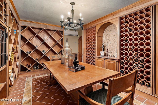 wine cellar featuring a textured ceiling, crown molding, an AC wall unit, and an inviting chandelier