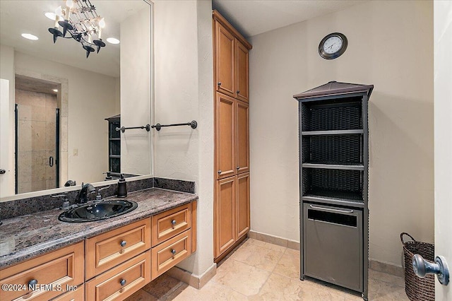 bathroom with an inviting chandelier, walk in shower, and vanity