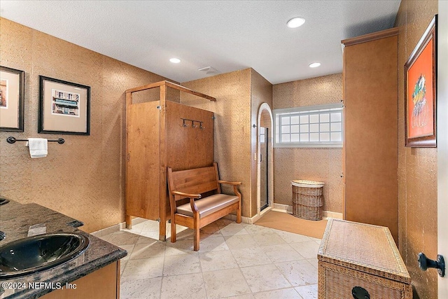 bathroom featuring walk in shower, vanity, and a textured ceiling