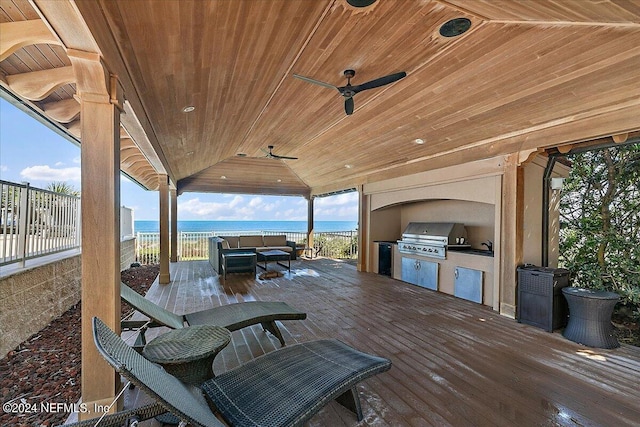 view of patio / terrace with ceiling fan, area for grilling, an outdoor kitchen, and a deck with water view