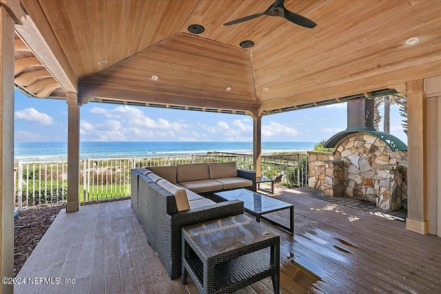 view of patio featuring ceiling fan, a deck with water view, a view of the beach, an outdoor living space, and a gazebo