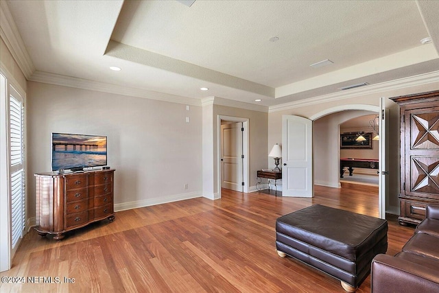 interior space with a textured ceiling, crown molding, a tray ceiling, and hardwood / wood-style flooring