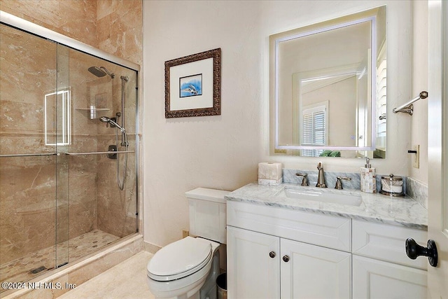 bathroom featuring a shower with door, vanity, and toilet