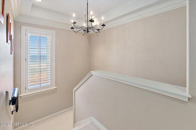 stairway with ornamental molding and an inviting chandelier