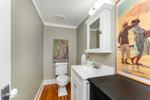 bathroom with a textured ceiling, vanity with extensive cabinet space, toilet, and hardwood / wood-style flooring