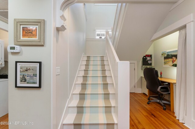 stairs with vaulted ceiling and light wood-type flooring