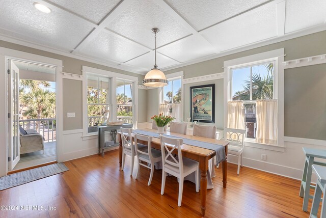 dining area featuring coffered ceiling and light hardwood / wood-style flooring