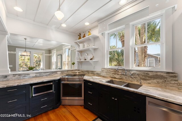 kitchen featuring a healthy amount of sunlight, stainless steel appliances, sink, and decorative light fixtures