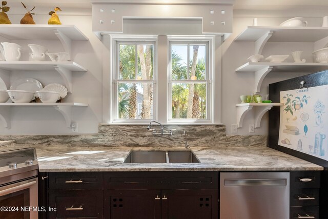 kitchen with range, sink, stainless steel dishwasher, dark brown cabinets, and light stone countertops