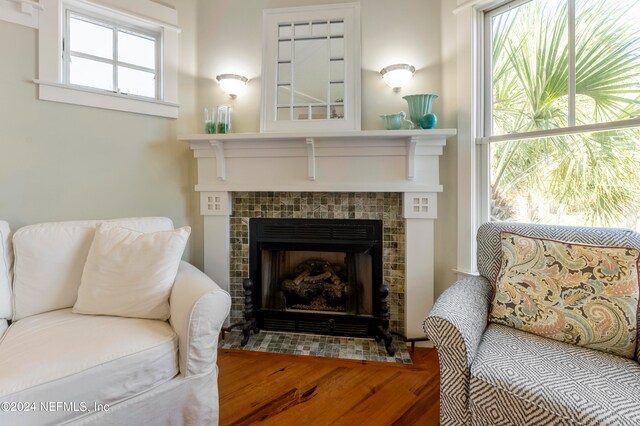 living area with wood-type flooring and a tiled fireplace