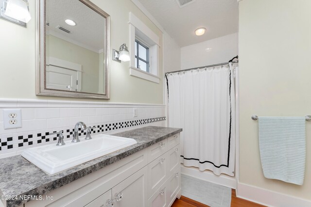 bathroom with backsplash, a textured ceiling, vanity, and hardwood / wood-style floors