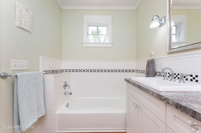 bathroom with ornamental molding, vanity, and a bath to relax in