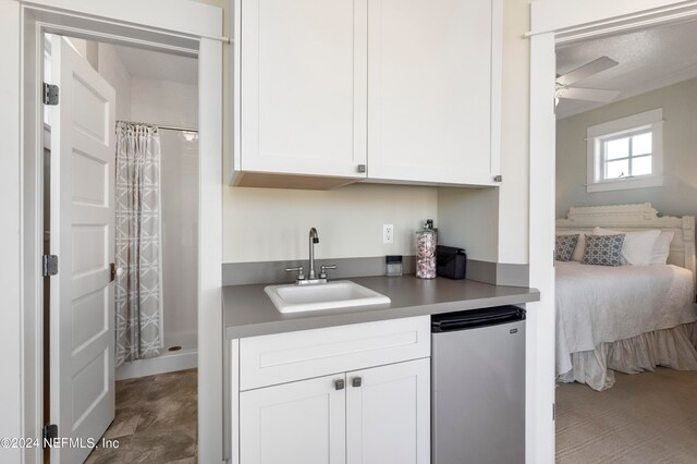 kitchen featuring sink, ceiling fan, refrigerator, and white cabinetry