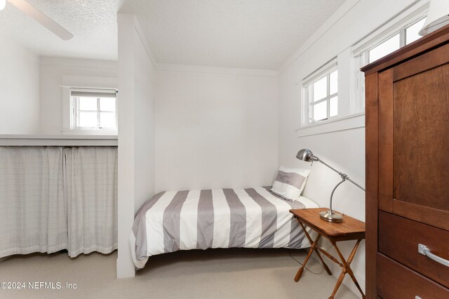 bedroom featuring a textured ceiling, ceiling fan, light carpet, and ornamental molding