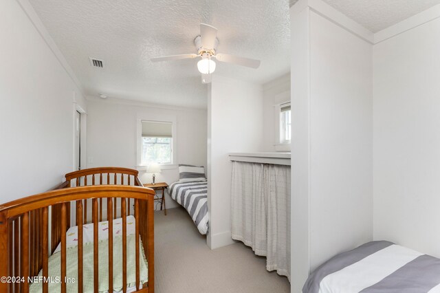 carpeted bedroom featuring ceiling fan and a textured ceiling