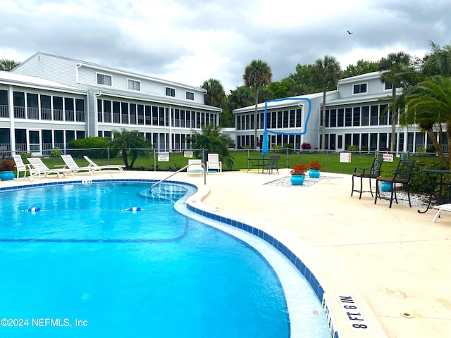 view of pool with a patio area, a sunroom, and a yard