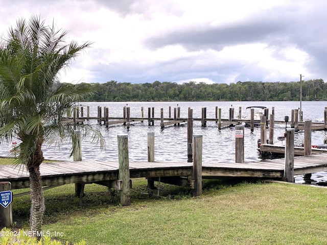 view of dock with a water view and a yard