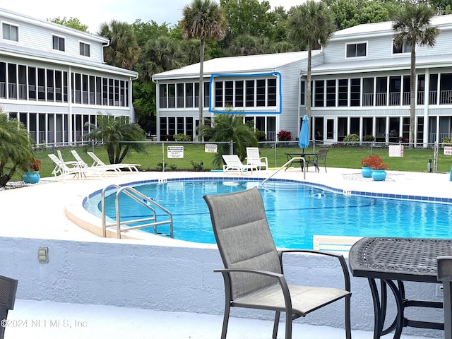 view of swimming pool featuring a patio area and a sunroom