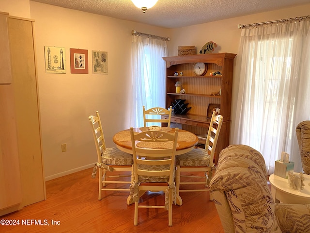 dining room with plenty of natural light, light hardwood / wood-style flooring, and a textured ceiling