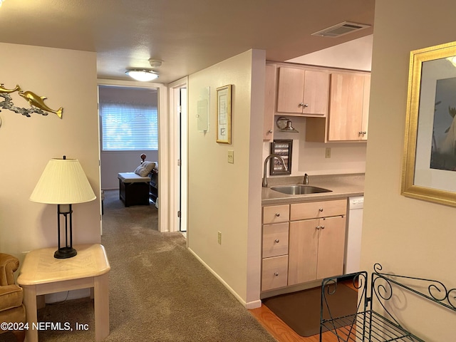 kitchen featuring sink, dark colored carpet, dishwasher, and light brown cabinetry