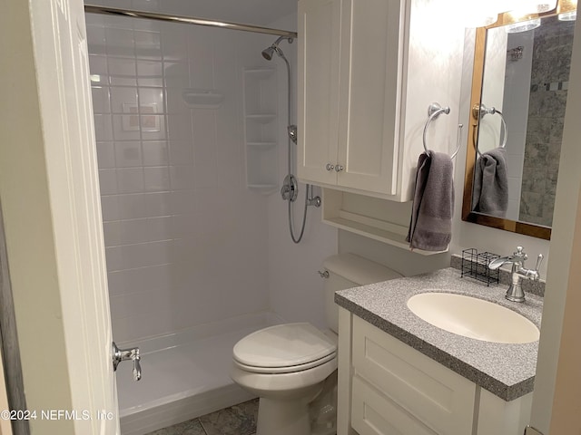 bathroom featuring tile flooring, toilet, large vanity, and tiled shower