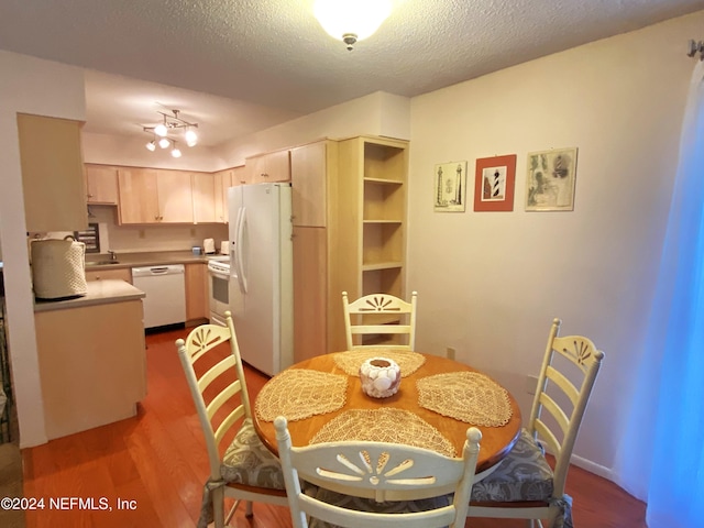 dining area featuring hardwood / wood-style floors, a textured ceiling, track lighting, and sink