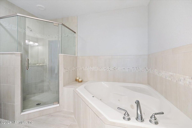 full bathroom with a shower stall and a tub with jets