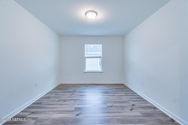 unfurnished room with hardwood / wood-style floors and a textured ceiling