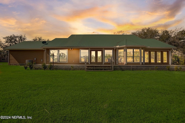 back house at dusk with a lawn