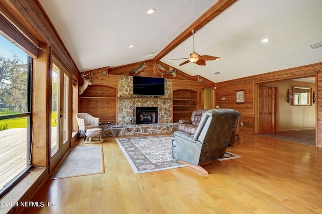 living room featuring built in features, wooden walls, light hardwood / wood-style floors, and ceiling fan