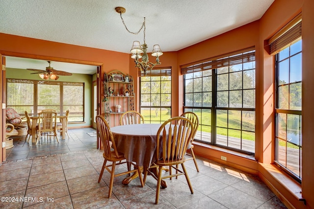 tiled dining room with a textured ceiling and ceiling fan with notable chandelier