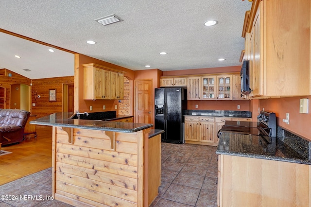 kitchen featuring wood walls, light hardwood / wood-style floors, kitchen peninsula, black appliances, and a textured ceiling