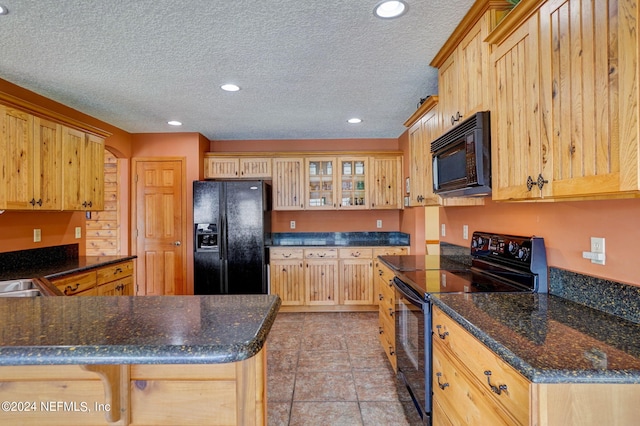 kitchen featuring black appliances, a breakfast bar, light tile floors, dark stone countertops, and a textured ceiling