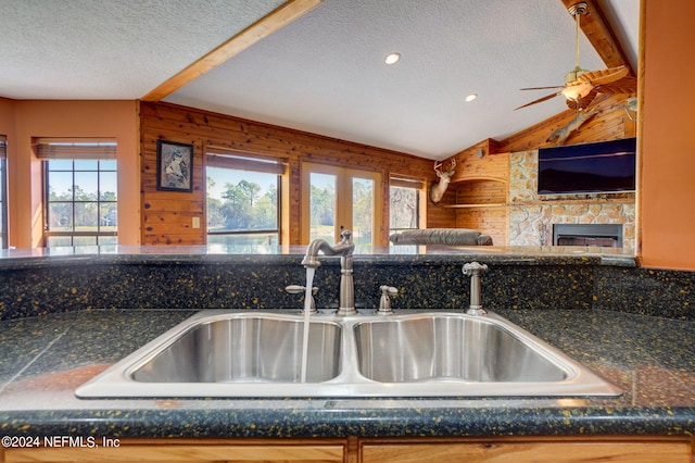 kitchen featuring a fireplace, wood walls, a wealth of natural light, and a textured ceiling